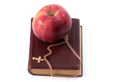 Olgun kırmızı bir elma ve altın haçlı dini bir kitap.