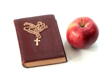 Olgun kırmızı bir elma ve altın haçlı dini bir kitap.