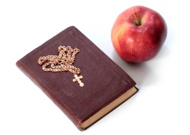 Olgun kırmızı bir elma ve altın haçlı dini bir kitap.