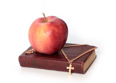 Olgun kırmızı bir elma ve altın haçlı dini bir kitap.