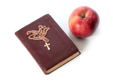 Olgun kırmızı bir elma ve altın haçlı dini bir kitap.