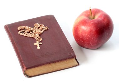 Olgun kırmızı bir elma ve altın haçlı dini bir kitap.