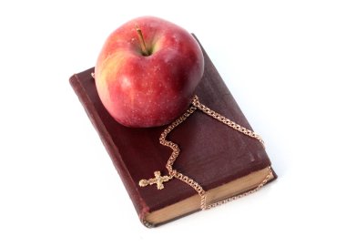 Olgun kırmızı bir elma ve altın haçlı dini bir kitap.