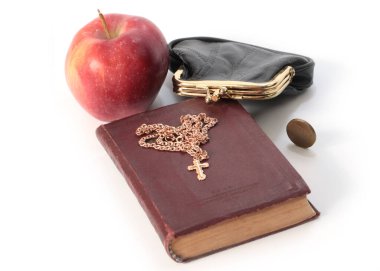 Metal bir para çantasının yanında olgun bir elma ve altın haçlı bir dini kitap.
