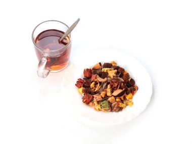 Bir bardak koyu siyah çay ve bir yığın kurutulmuş aromatik ot.