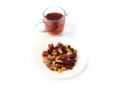 Bir bardak koyu siyah çay ve bir yığın kurutulmuş aromatik ot.