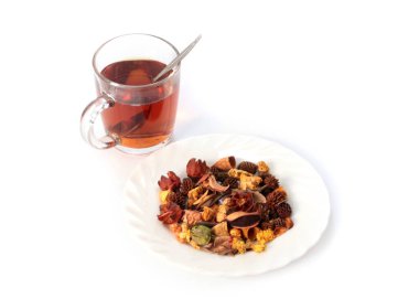 Bir bardak koyu siyah çay ve bir yığın kurutulmuş aromatik ot.