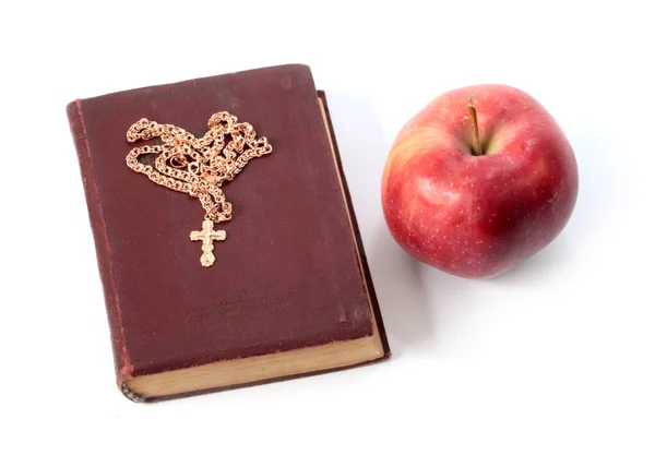 一个成熟的红苹果和一本有金色十字架的宗教书籍 — 图库照片