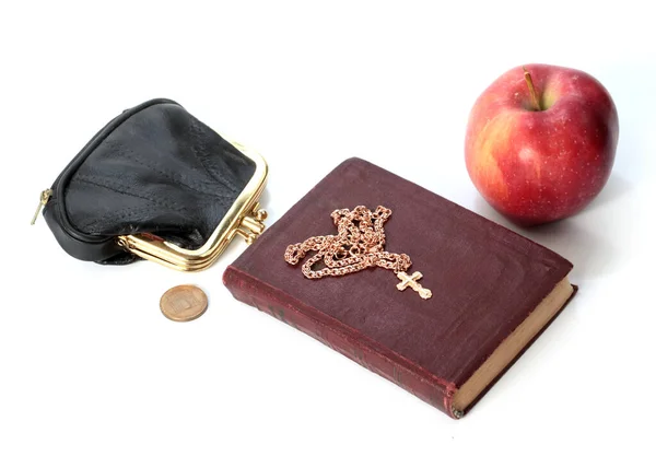 一个成熟的苹果 旁边有一个装有金属硬币的钱包和一本有金十字架的宗教书籍 — 图库照片