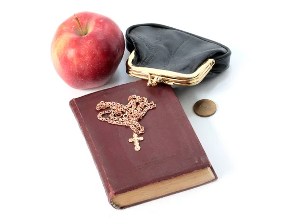 一个成熟的苹果 旁边有一个装有金属硬币的钱包和一本有金十字架的宗教书籍 — 图库照片