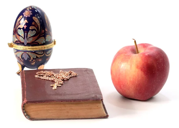一个成熟的苹果 旁边有一本宗教书籍 上面有一个金色的十字架和一个复活节彩蛋 — 图库照片