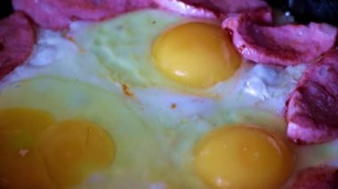 Sabah kahvaltısı için yağda yumurta ve sosis pişiriyorum.