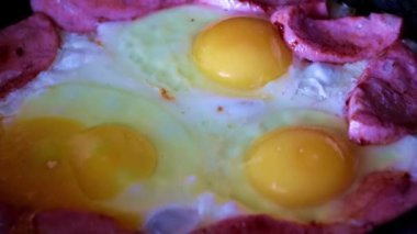 Sabah kahvaltısı için yağda yumurta ve sosis pişiriyorum.