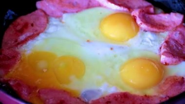 Sabah kahvaltısı için yağda yumurta ve sosis pişiriyorum.