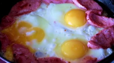 Sabah kahvaltısı için yağda yumurta ve sosis pişiriyorum.