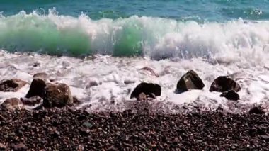 Fırtınalı deniz dalgaları ve aktif dinlenme yeri olarak bir çakıl taşı plajı.