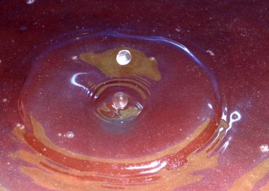 Mikroplarla enfekte olmuş kirli bir su damlası kirlenmiş sıvının yüzeyine düşer.