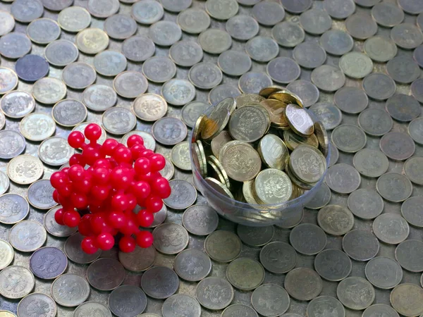 a pile of metal coins the Russian ruble and a plastic model of a disease causing virus microbe