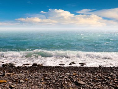 Deniz kıyısının çakıl taşlı kumsalında güzel mavi gökyüzü