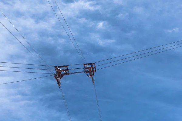 Cable car wires and pulleys suspended in cloudy sky