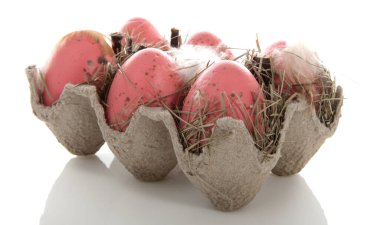 Beyaz arka planda pembe paskalya yumurtaları olan yumurta tutucu.