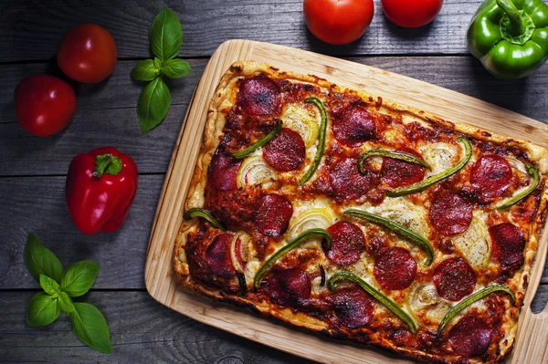 Pizza fatta in casa con salame piccante su un tavolo di legno Fotografia Stock