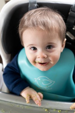 Messy baby boy eating avocado