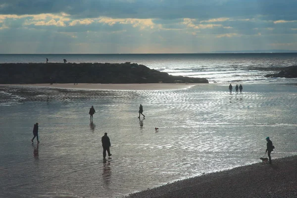 Sylwetki Ludzi Chodzących Mokrej Piaszczystej Plaży Sidmouth Devon — Zdjęcie stockowe
