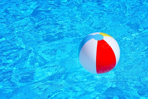 Colorful inflatable ball floating in swimming pool — Stock Photo, Image