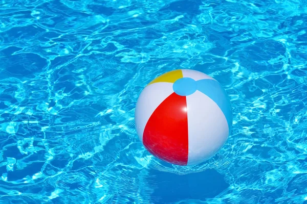 Colorful inflatable ball floating in swimming pool — Stock Photo, Image