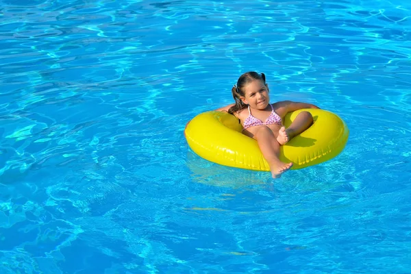 Suloinen lapsi rentouttava uima-altaassa — kuvapankkivalokuva