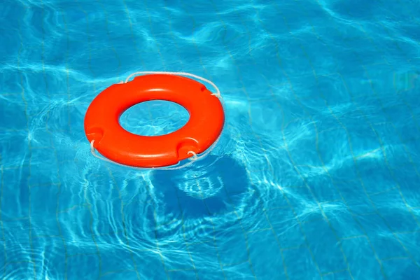 Colorful lifebuoy floating in swimming pool — Stock Photo, Image