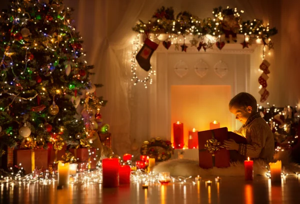 Niño abriendo regalo de Navidad, Niño mirando a la luz caja de regalo, Noche de Navidad — Foto de Stock