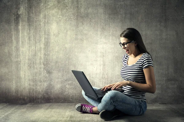 Frau mit Laptop, glückliches Mädchen mit Brille am Notizbuch, junger Erwachsener sitzt mit Computer auf dem Boden — Stockfoto
