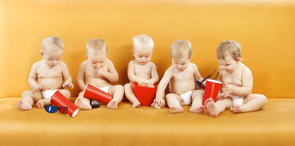 Bebé comiendo palomitas de maíz, Grupo de niños viendo televisión, niños de un año de edad —  Fotos de Stock