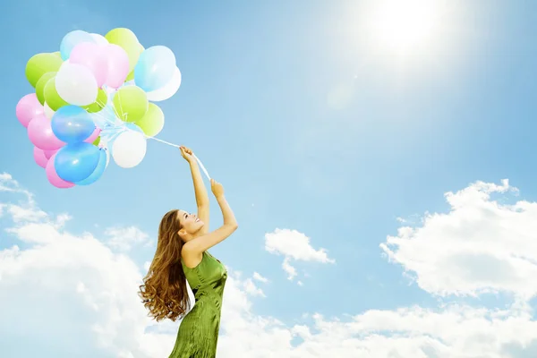 Frau fliegt auf Ballons, glückliches Mädchen mit buntem Ballonstrauß, sonniger blauer Himmel — Stockfoto
