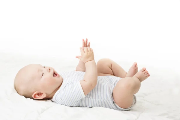 Baby auf dem Rücken liegend, glückliches Kleinkind im blauen Body, Kind auf weißer Decke liegend — Stockfoto