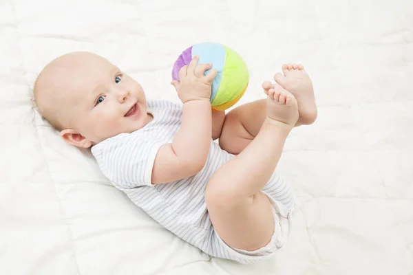 Giocattolo del bambino gioca palla, Ragazzo felice sdraiato sulla schiena che gioca giocattoli morbidi, Bambino neonato sul bianco — Foto Stock