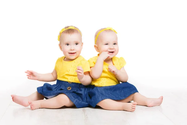 Baby's tweeling, twee Kids meisjes zitten op de vloer, gelukkige kinderen zusters wit geïsoleerd — Stockfoto