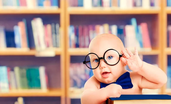 Умный ребенок в очках с книгой, маленький ребенок в школьной библиотеке, концепция образования — стоковое фото