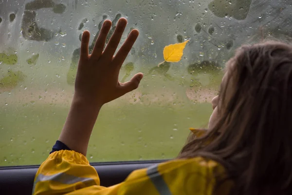 the child put his hand on the foggy car window, looking at the yellow lea