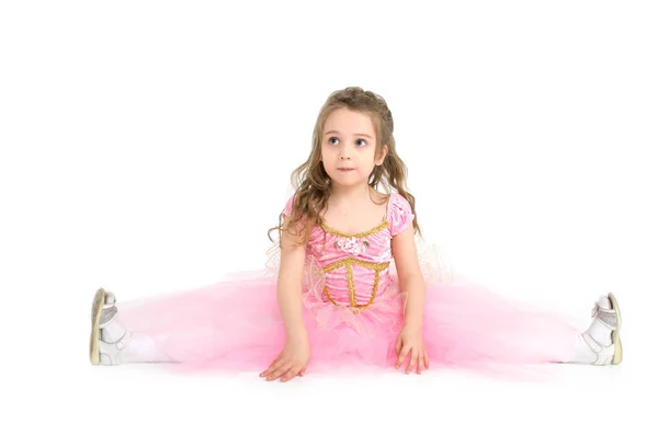 Little girl sitting on a twine in a pink princess dress isolated on white background