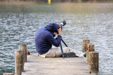 Gölün rıhtımında fotoğraf çeken adam.