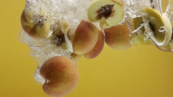 Персиковые половинки падают в воду в замедленной съемке . — стоковое видео