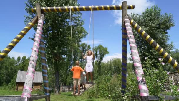 Young girl and two boys  swinging high — Stock Video