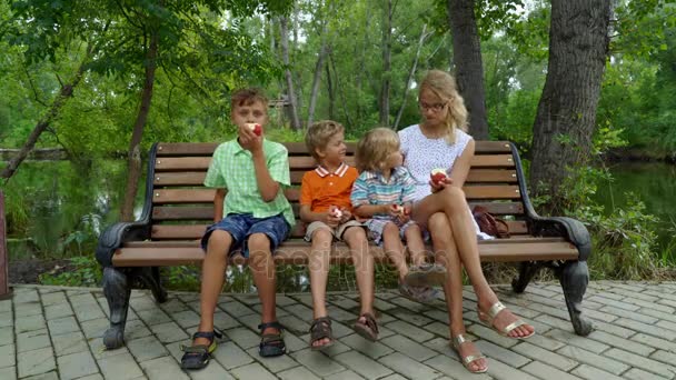 Enfants avec maman assise sur le banc et mangeant des pommes — Video