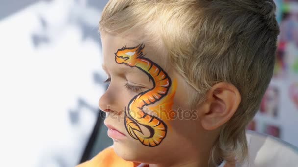 Professional makeup artist drawing dragon on a face of a child — Stock Video