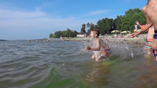 Niños saltando en el agua de mar en la playa — Vídeos de Stock