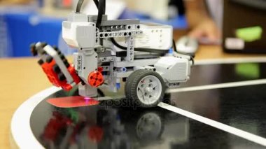 Programlanmış oyuncak araba kırmızı kare tuğla kaldırır.