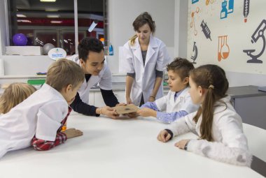 Teknisyenler çocuklara talaşlı ve bir mıknatıs ile deneme göstermek.